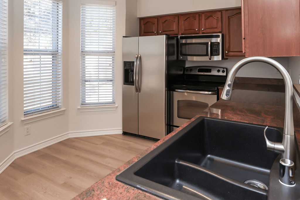 A kitchen with a black sink and stainless steel appliances.